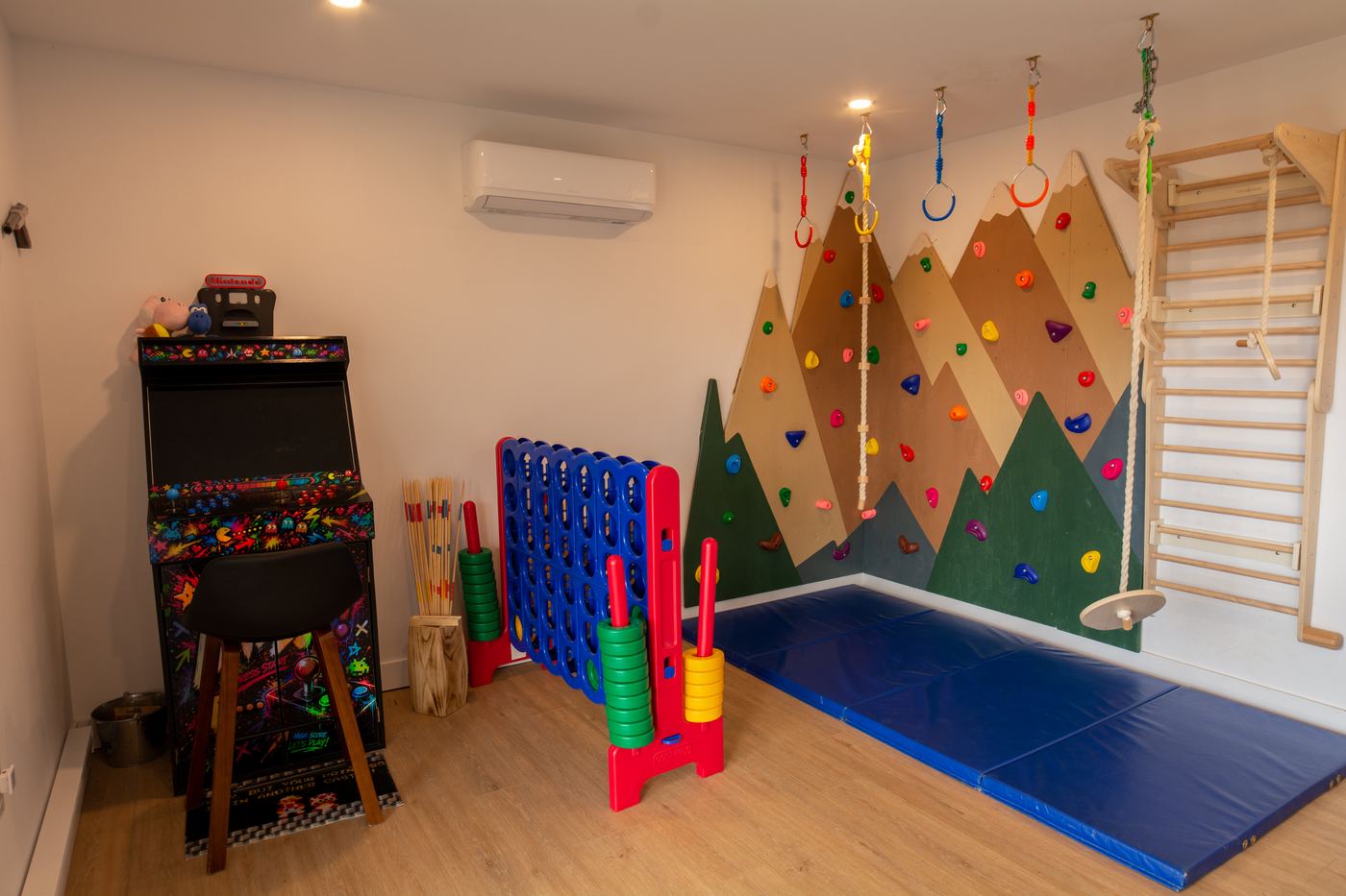 Salle de jeux avec mur d'escalade, arcade et tapis